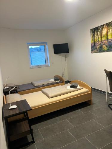 a bedroom with a bed and a desk and a television at Pension Imhof in Oyten