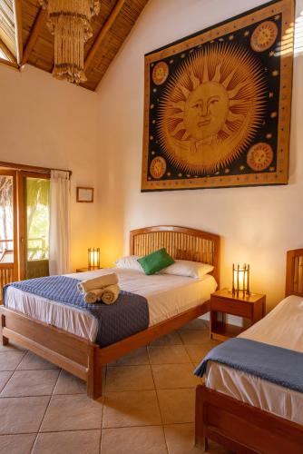 two beds in a room with a sun picture on the wall at Soleil Bungalows in Los Órganos