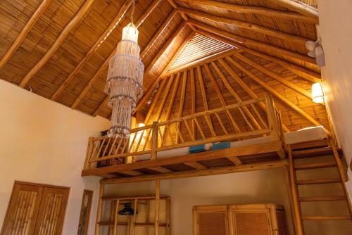 a loft bed in a room with a wooden ceiling at Soleil Bungalows in Los Órganos
