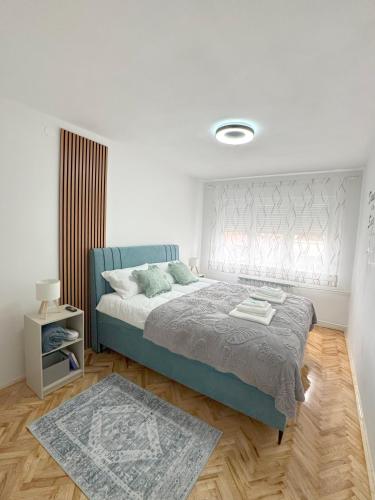 a white bedroom with a bed and a rug at HeyYou Apartment in Bjelovar