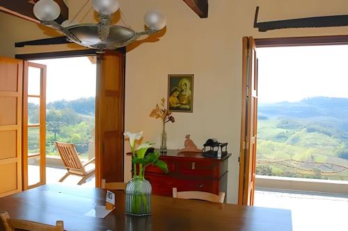 a dining room with a table and a large window at Pousada Borghetto – Charme e Exclusividade no Vale dos Vinhedos in Bento Gonçalves