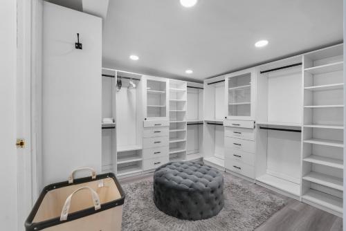 a master closet with white cabinets and a black ottoman at Spacious 4-bedroom Glendora Super House in Glendora
