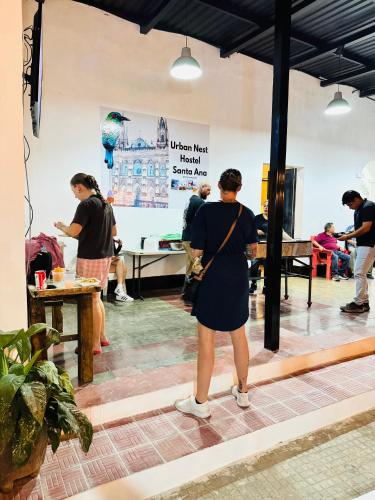 a woman in a black dress standing in a room at Urban Nest Hostel in Santa Ana