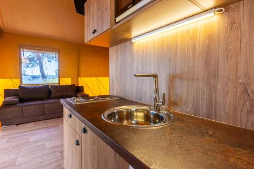 a kitchen with a sink and a couch at Adria Glamping luxury tents Camping Poljana Mali Lošinj in Mali Lošinj
