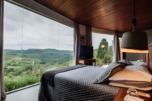 a bedroom with a bed and a large window at Pousada Borghetto – Charme e Exclusividade no Vale dos Vinhedos in Bento Gonçalves