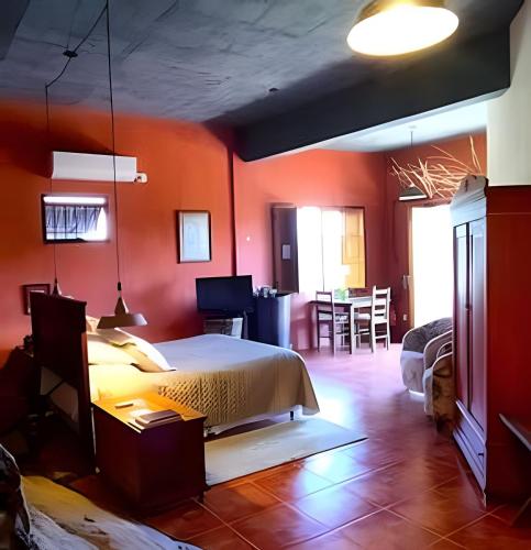 a bedroom with orange walls and a bed and a table at Pousada Borghetto – Charme e Exclusividade no Vale dos Vinhedos in Bento Gonçalves