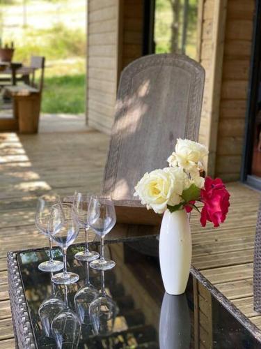 un vase avec des fleurs sur une table et des verres à vin dans l'établissement Maison - piscine - Vue vignobles coeur de nature, à Roquetaillade