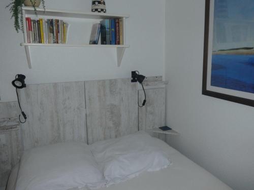 - une chambre avec un lit et une étagère avec des livres dans l'établissement T2 bord de mer, à Pornic