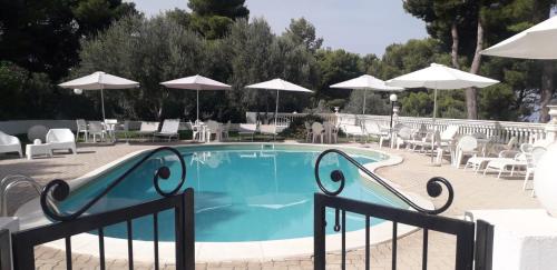 a swimming pool with chairs and tables and umbrellas at Villa Nunziatella Badia in Trappeto