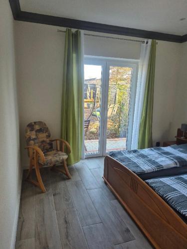 a bedroom with a bed and a chair and a window at Ferienwohnung Uhlenbusch Paradise in Friesoythe