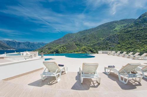 a group of chairs and a swimming pool with mountains at Lavender Bay D04 in Donji Morinj