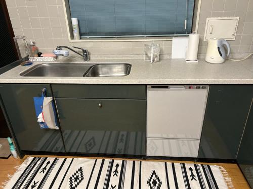 a kitchen counter with a sink and a dishwasher at Airportside Chillhouse in Toyonaka
