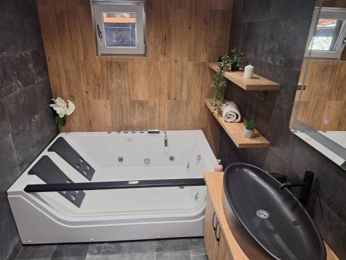 a bathroom with a white tub and a black chair at Apartmani Lux Filipovic in Smederevo