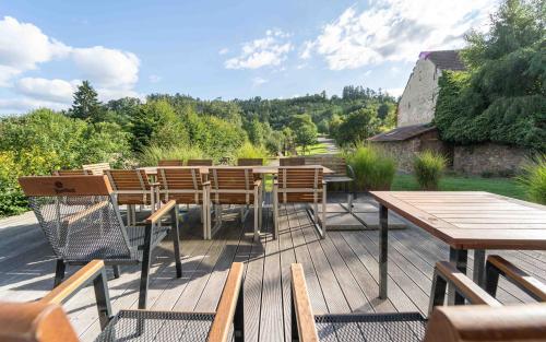 a wooden deck with wooden tables and chairs on it at Porčův mlýn in Býkovice