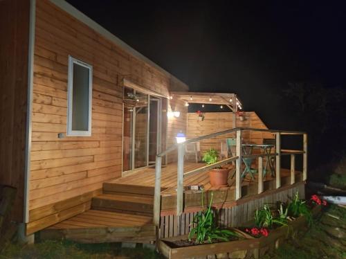 a wooden house with a deck at night at Le ty cocon in Saint-Frégant