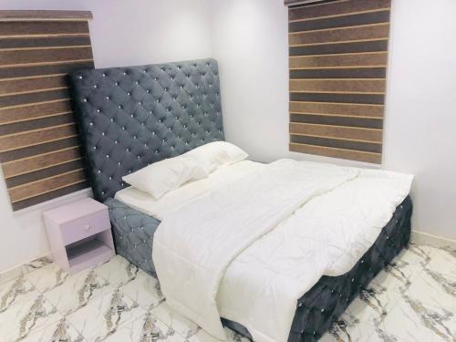 a bedroom with a large bed with a padded headboard at TY LUX Apartment in Mowe