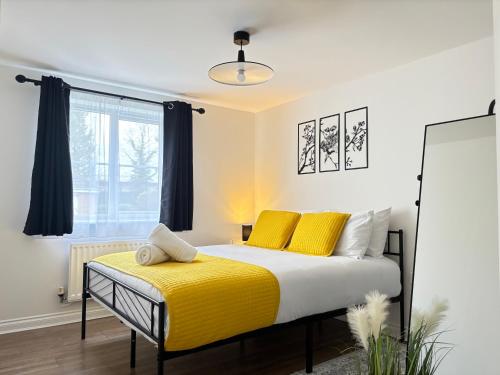 a bedroom with a bed with yellow sheets and a window at 2BR 2BA Flat - King Beds - Free Parking - Near LGW Airport in Crawley