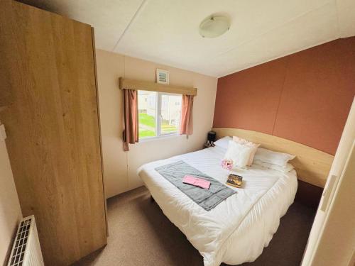een kleine slaapkamer met een bed en een raam bij 3 Bedroom 2 Bathroom Caravan Charlie Delta in Saint Osyth