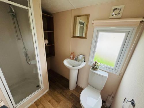 een badkamer met een toilet, een wastafel en een douche bij 3 Bedroom 2 Bathroom Caravan Charlie Delta in Saint Osyth