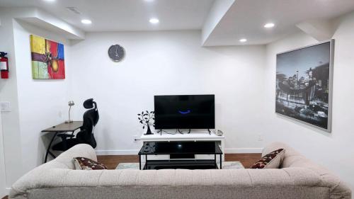 a living room with a couch and a flat screen tv at Cozy & Spacious 1-Bedroom SW Calgary near SpruceMeadows in Calgary