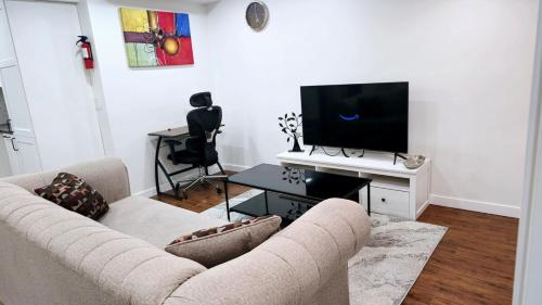 a living room with a couch and a flat screen tv at Cozy & Spacious 1-Bedroom SW Calgary near SpruceMeadows in Calgary