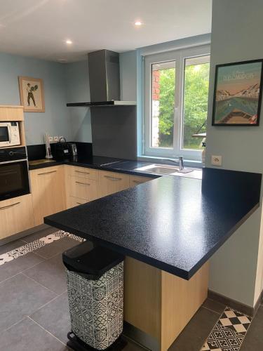 une cuisine avec un comptoir noir dans une pièce dans l'établissement Maison campagne 2chambres avec jardin, à Watten