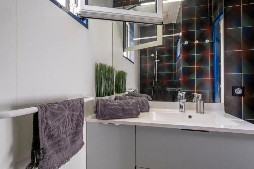 une salle de bain avec un lavabo et un miroir dans l'établissement Maison avec jardin, à Sainte-Marie de Ré