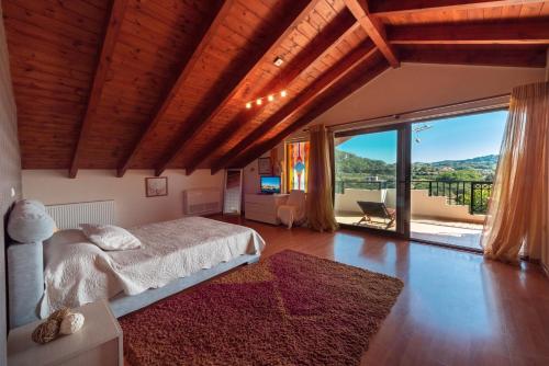 a bedroom with a bed and a large window at Filerimos Hillside Villa in Pastida