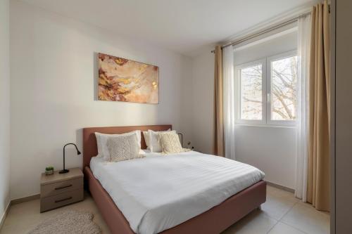 a bedroom with a bed with white sheets and a window at Regalia Suites - Free Parking in Lugano