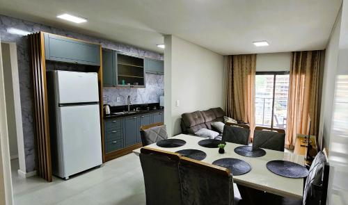uma cozinha com uma mesa e uma geladeira branca em Apartamento 3 quartos com suíte em Itapema