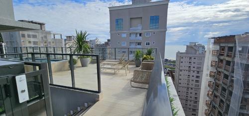 uma varanda com cadeiras e mesas num edifício em Apartamento 3 quartos com suíte em Itapema