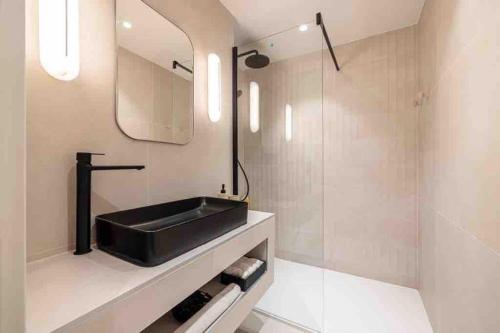 une salle de bain avec un lavabo noir et un miroir dans l'établissement Pasteur Luxury apartment la Croisette, à Cannes