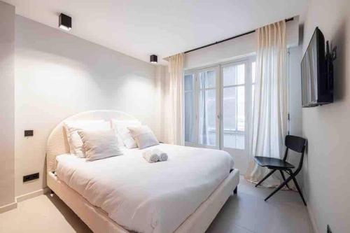 une chambre avec un grand lit blanc et une fenêtre dans l'établissement Pasteur Luxury apartment la Croisette, à Cannes