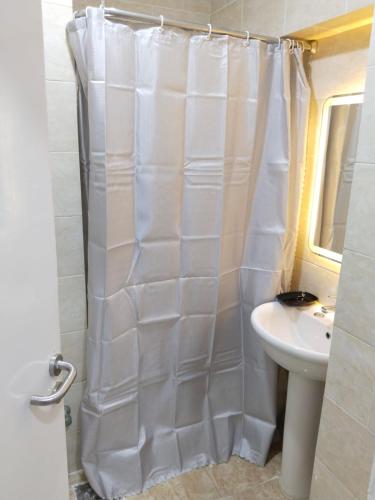 a white shower curtain in a bathroom with a sink at Aquarium Seaview accomodations in Hurghada