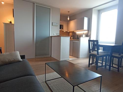 un salon avec un canapé et une table et une cuisine dans l'établissement Appartement Saint-Malo vue mer, à Saint-Malo