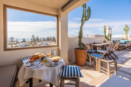 een eetkamer met een tafel en stoelen en een groot raam bij Riad Horizon in Essaouira