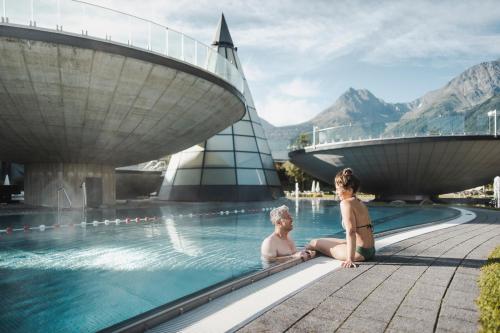 two women sitting in a swimming pool at a resort at Aktivhotel Waldhof in Oetz