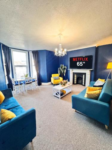 a living room with two blue couches and a fireplace at Spacious Central and Chic 65 TV in Plymouth
