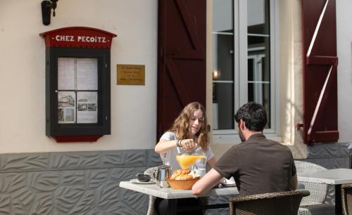 a man and a woman sitting at a table with a drink at Hotel Restaurant Pecoitz in Saint-Jean-Pied-de-Port
