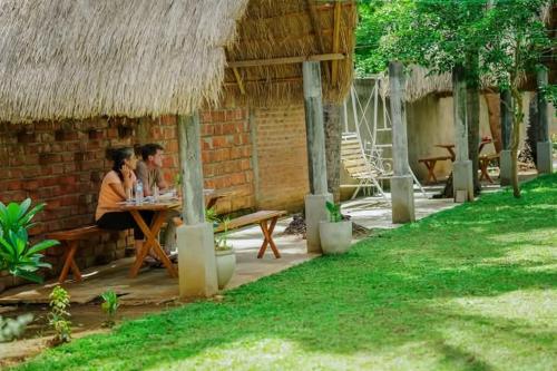 two people sitting at a table outside of a hut at Hotel ART HAVEN in Diwulankadawala