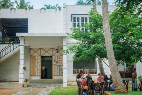 a group of people sitting at a table in front of a building at Hotel ART HAVEN in Diwulankadawala