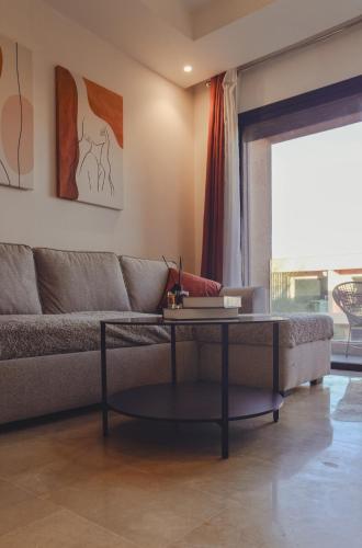 a living room with a couch and a table at Eva cosy - Clim, Wifi, Jardin à 10min de l'Aéroport in Marrakech