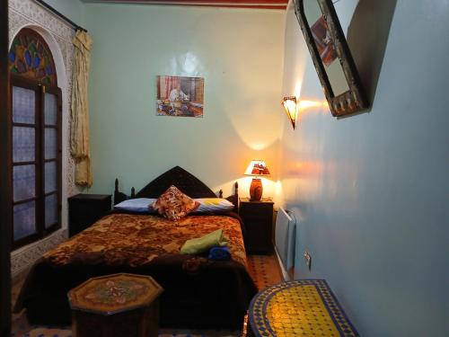 a bedroom with a bed and a table and a lamp at Riad Idrissi in Meknès