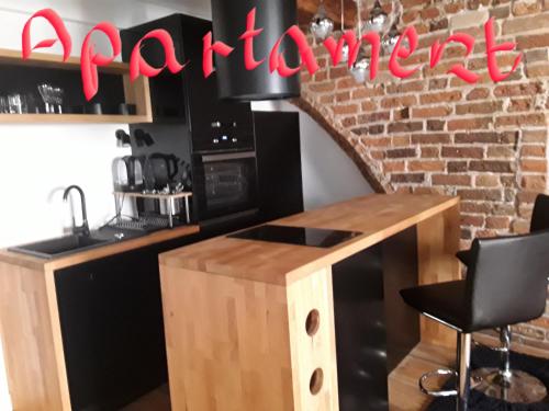a kitchen with a counter and a brick wall at Old Town Mostowa - I piętro - Apartament lub pokój in Toruń