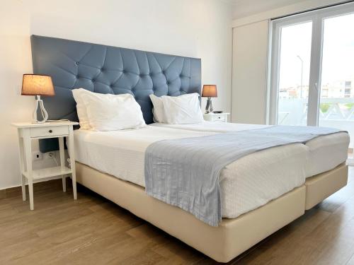 a large bed with a blue headboard in a bedroom at River Inn - Duna Parque Group in Vila Nova de Milfontes