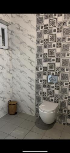 a bathroom with a toilet and a tile wall at Asayl resort in Baghdad