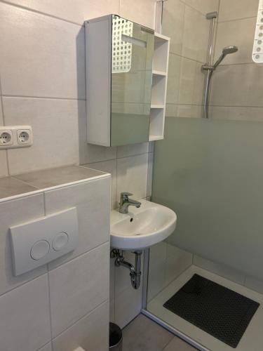 a white bathroom with a sink and a shower at Ferienhuus Tüütje in Wolthusen