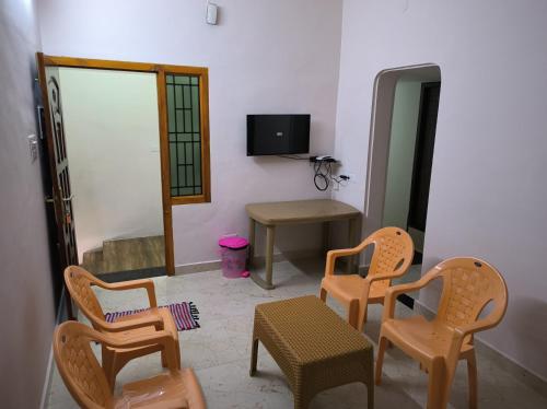 a room with chairs and a table and a television at La villa Rani KK Nagar in Madurai