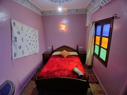 a bedroom with a red bed with a window at Riad Idrissi in Meknès