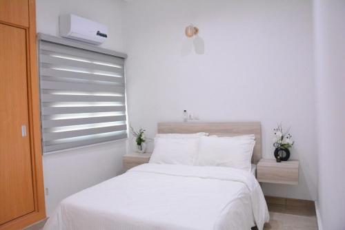 a bedroom with a bed with white sheets and a window at Jod & Naic Appartement in Abidjan
